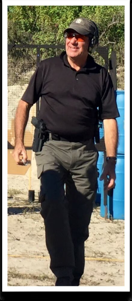 John Johnson in tactical gear walking at an outdoor shooting range